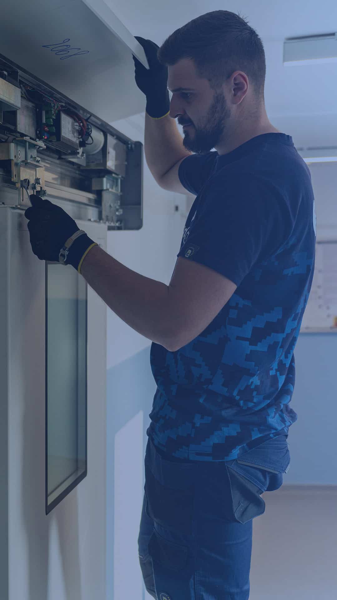 Tehnician reparând sau verificând un panou electric pentru uși automate.